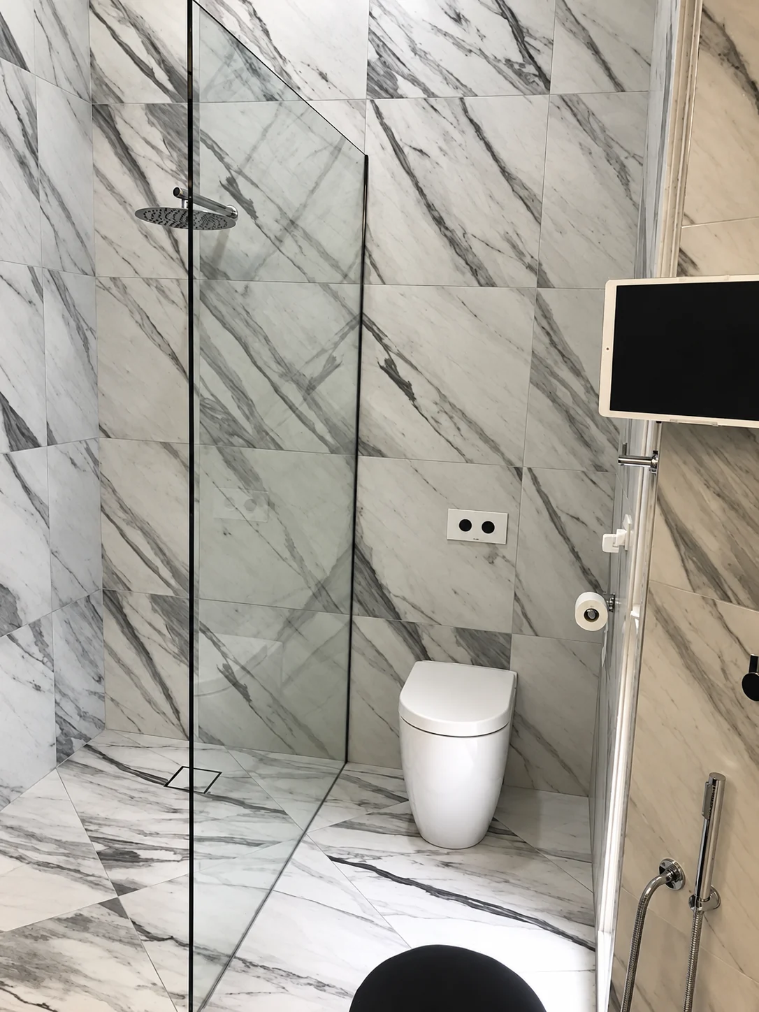 Shower and toilet fixtures in a tiled bathroom.
